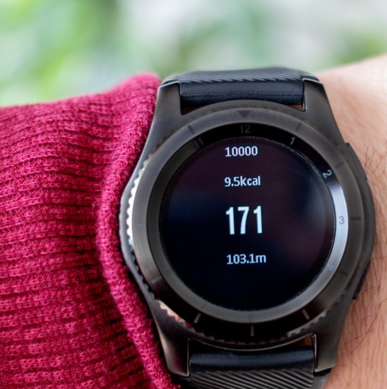 Closeup of a black smart watch on someone's arm displaying fitness stats.