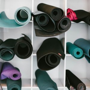 An assortment of yoga mats rolled up and placed inside cubbies outside of a fitness studio.