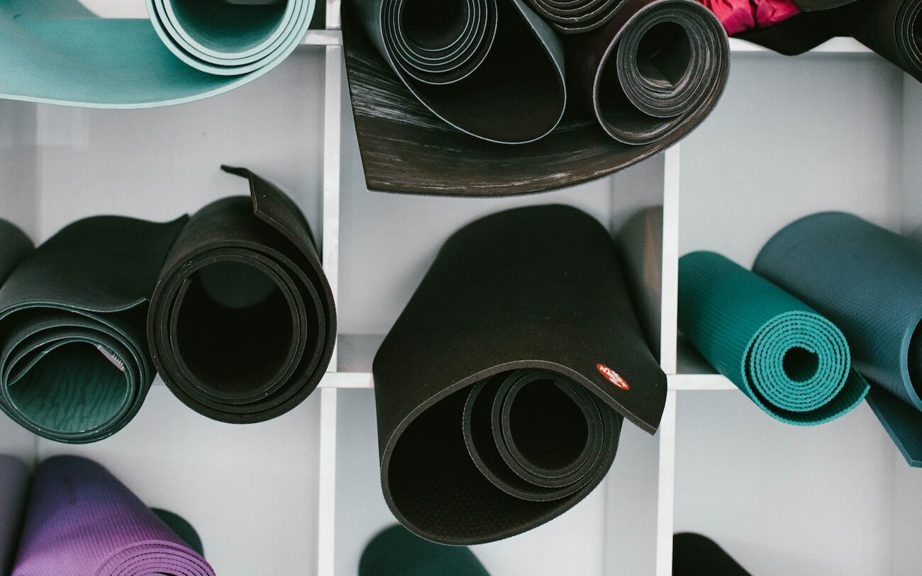 An assortment of yoga mats rolled up and placed inside cubbies outside of a fitness studio.